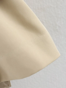 Gros plan du tissu d'un trench-coat kaki montrant la texture sergée et les coutures