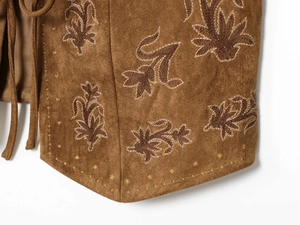 Detailed close-up of floral embroidery on brown suede vest with fine decorative stitching