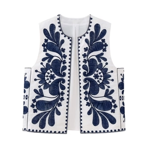 Detail of blue floral embroidery and paisley patterns on a white ethnic style vest