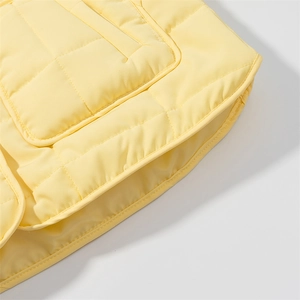 Detailed close-up of yellow quilted fabric with diamond stitching and neat piping edges