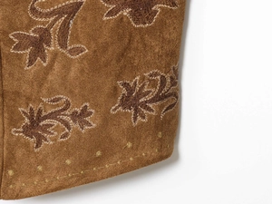 Macro shot of khaki suede vest fabric with intricate floral embroidery and stitching