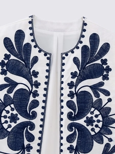 Close-up of ethnic style navy blue floral embroidery on white open-front vest