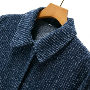 Close-up of deep blue textured denim jacket collar and woven fabric details