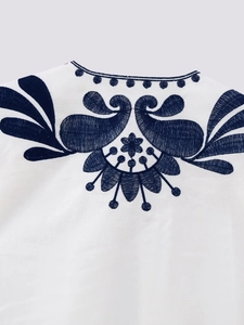 Detailed close-up of navy blue floral embroidery on white bohemian vest neckline
