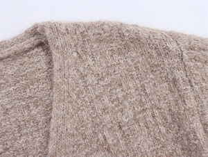 Nahaufnahme der beigen Grobstricktextur und des weichen Stoffes an der Damenstrickjacke
