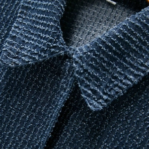 Detail of tweed denim jacket collar with textured fabric and size tag on wooden hanger