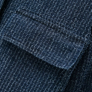 Close-up of textured dark blue denim jacket with flap pocket detail and white marl pattern