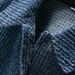 Macro view of navy blue denim jacket showing textured fabric and silver metallic buttons