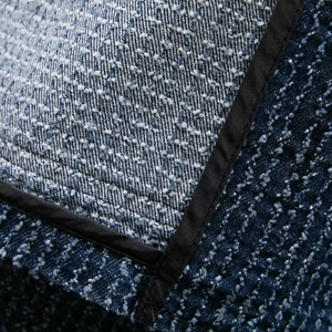 Macro detail of blue tweed jacket fabric showing intricate texture and black satin trim