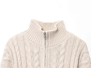 Detail of beige cable-knit sweater featuring a mock neck and metallic half-zip closure