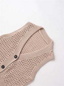 Détail de gilet en maille ajourée beige avec boutons noirs et motif losange
