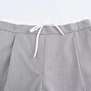 Detalle de pantalón gris de pierna ancha con cintura elástica blanca de doble capa y cordón