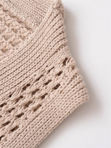 Gros plan du gilet en maille beige avec détails ajourés et textures finement tricotées