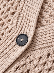 Détail de la maille ajourée abricot avec un bouton noir sur le haut sans manche