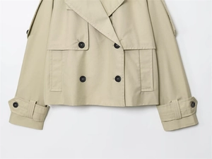 Detail of short double-breasted khaki windbreaker with black buttons and cuff straps