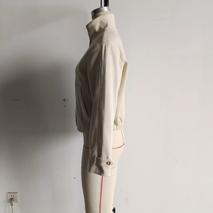 Détail de la veste crème à col montant avec texture suédée et boutons aux poignets