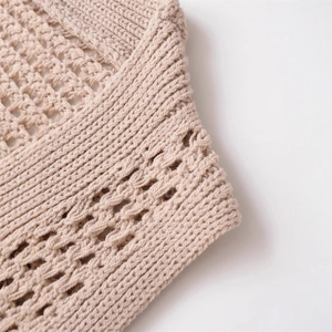 Gros plan sur un gilet en maille beige pour femme avec crochet ajouré et bords côtelés