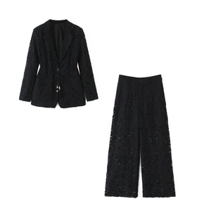 Close-up of intricate floral lace texture and belt detail on black suit jacket