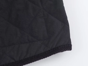Detail of black quilted jacket showing diamond stitching and corduroy trim edges