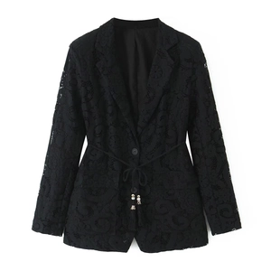 Detail of black lace blazer featuring intricate cutout patterns and waist drawstring tassels