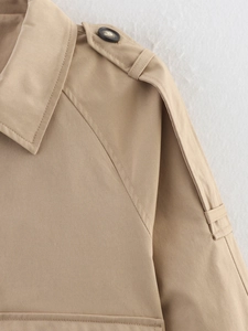 Détail de la patte d'épaule et du revers d'un trench-coat kaki avec texture en sergé