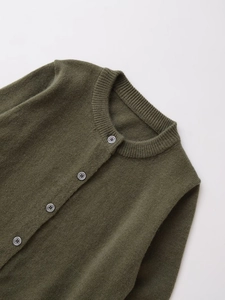 Macro detail of dark olive green knit cardigan with round neck and grey buttons
