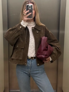 Detail of brown faux suede jacket layered with lace collar top and chic burgundy clutch bag