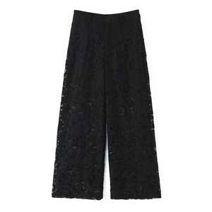 Detail of high-waisted black lace wide-leg trousers with intricate floral hollow patterns