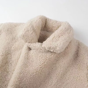 Detail of warm beige faux shearling coat featuring a soft teddy texture and lapel collar