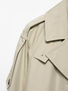Detail of khaki trench coat featuring shoulder epaulettes and classic lapel collar fabric