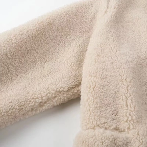 Close-up of cream faux shearling fabric showing soft texture and sleeve stitching detail
