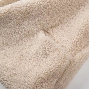 Close-up macro view of premium beige lamb fleece fabric showing soft textured fibers
