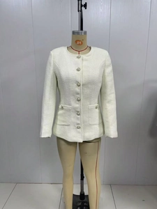Detail of white tweed jacket showing woven texture and elegant pearl button closure