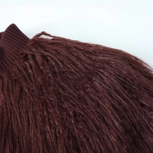 Détail macro de la texture en fausse fourrure bordeaux et du col en maille de la veste