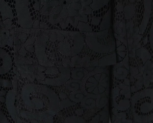 Close-up detail of floral hollow lace fabric with pocket flap on black blazer jacket