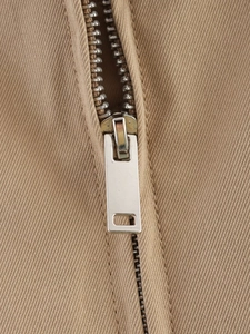Détail macro d'une fermeture éclair en métal argenté sur trench-coat en sergé kaki