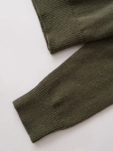 Close-up of ribbed cuffs on a dark olive green knit sweater with clear fabric texture