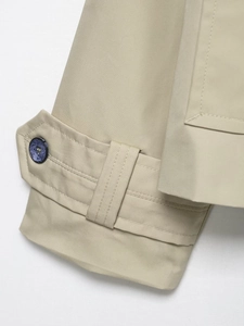 Detail of adjustable khaki trench coat cuffs with marble pattern button and twin stitching
