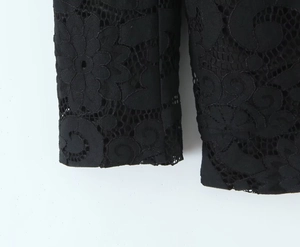 Detailed close-up of intricate black floral lace pattern and hollow embroidery texture