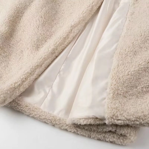 Close-up of off-white faux shearling fabric with smooth satin lining for winter warmth