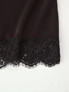 Detailed view of black satin fabric with intricate eyelash lace trim and floral patterns
