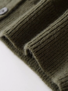 Close-up of military green ribbed knit texture and dark grey button on the sweater