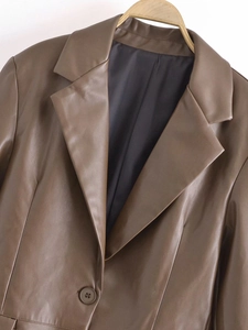 Detail shot of a brown faux leather blazer featuring a notched lapel and smooth texture