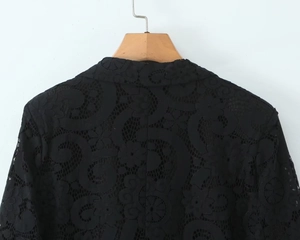 Detailed view of black hollow-out lace blazer featuring intricate floral patterns on a hanger