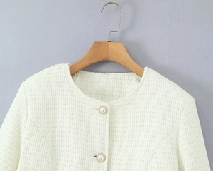 Detail of tweed fabric texture and decorative pearl buttons on the white jacket