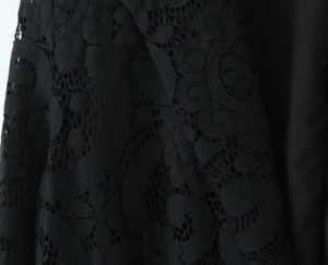 Macro detail of intricate black floral lace pattern and hollow mesh embroidery texture