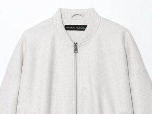 Detail of ribbed collar and metallic zipper on light gray oversized bomber jacket