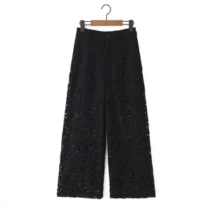 Detail of elegant black hollow lace wide-leg trousers with intricate spiral patterns