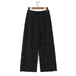 Detail of elegant black lace wide-leg trousers with intricate floral hollow patterns