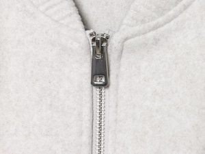 Macro detail of silver metal zipper and thick light grey fleece fabric on bomber jacket